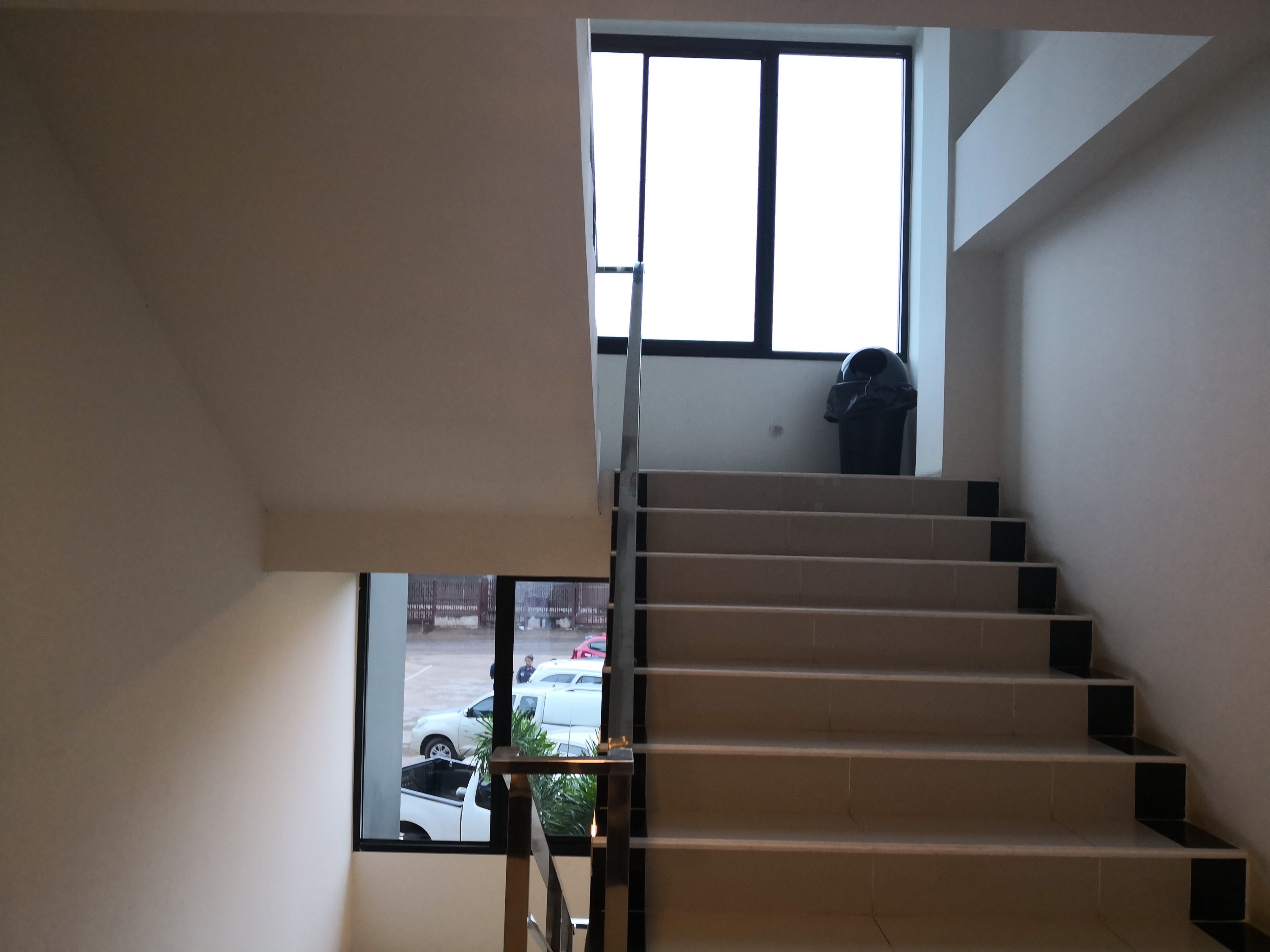 A staircase with a view of parked cars outside.