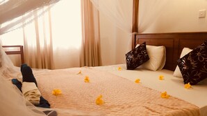 Ein Hotelzimmer mit Bett, Baldachin und einem Fenster mit Vorhängen.
