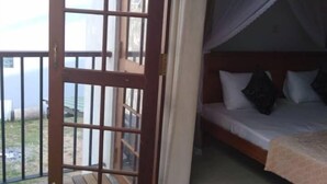 Ein Zimmer mit Holzboden, einem Bett mit Kissen und einem Fenster mit Blick ins Freie.