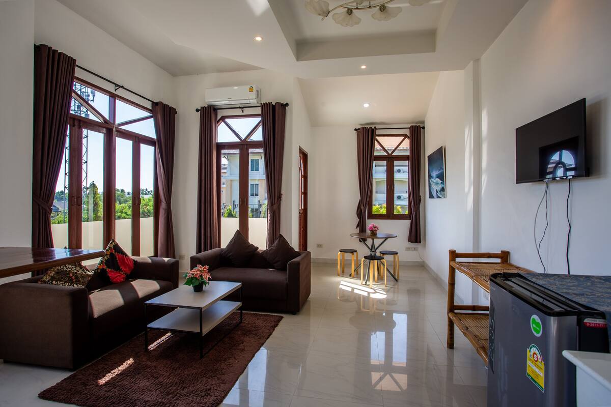 A spacious living area with a sofa, coffee table, and a TV mounted on the wall.
