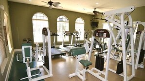 Un gimnasio con cintas de correr, máquinas de pesas y un banco verde para ejercicios.