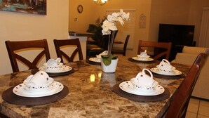 A dining table set with white teapots and plates, surrounded by wooden chairs. - Aco66067 - Lake Berkley - 4 Bed 2 Baths Villa (Kissimmee)