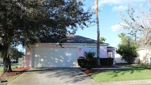 A single-story house with a garage, surrounded by trees and a well-maintained lawn. - Aco66067 - Lake Berkley - 4 Bed 2 Baths Villa (Kissimmee)