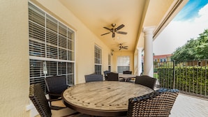 An outdoor patio with a round table and wicker chairs, ceiling fans, and a view of the neighborhood. - Aco66067 - Lake Berkley - 4 Bed 2 Baths Villa (Kissimmee)