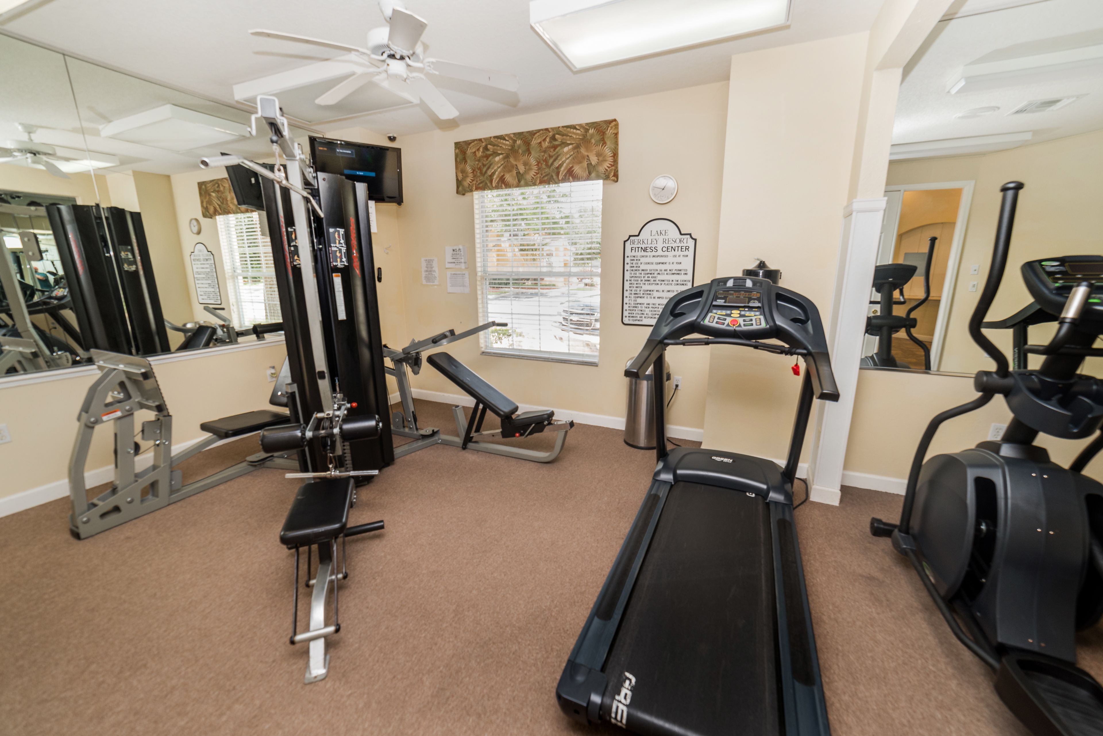 A gym with a treadmill, elliptical, and weight machines.