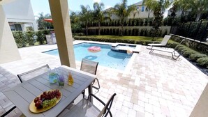 Un espace piscine aménagé avec une table pour les repas, un fauteuil de relaxation et un jacuzzi.
