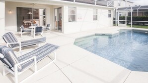 Un espace piscine avec des chaises longues et un patio couvert.