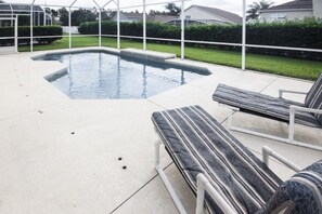 Une piscine avec des chaises longues et un espace patio couvert.