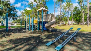 Une aire de jeux avec un toboggan, des structures d’escalade et des balançoires.