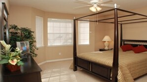 A four-poster bed with a canopy, a bedside table with a lamp, and a potted plant on a dresser. - Tr307 - Terrace Ridge - 3 Bed 2 Baths Condo (Davenport)