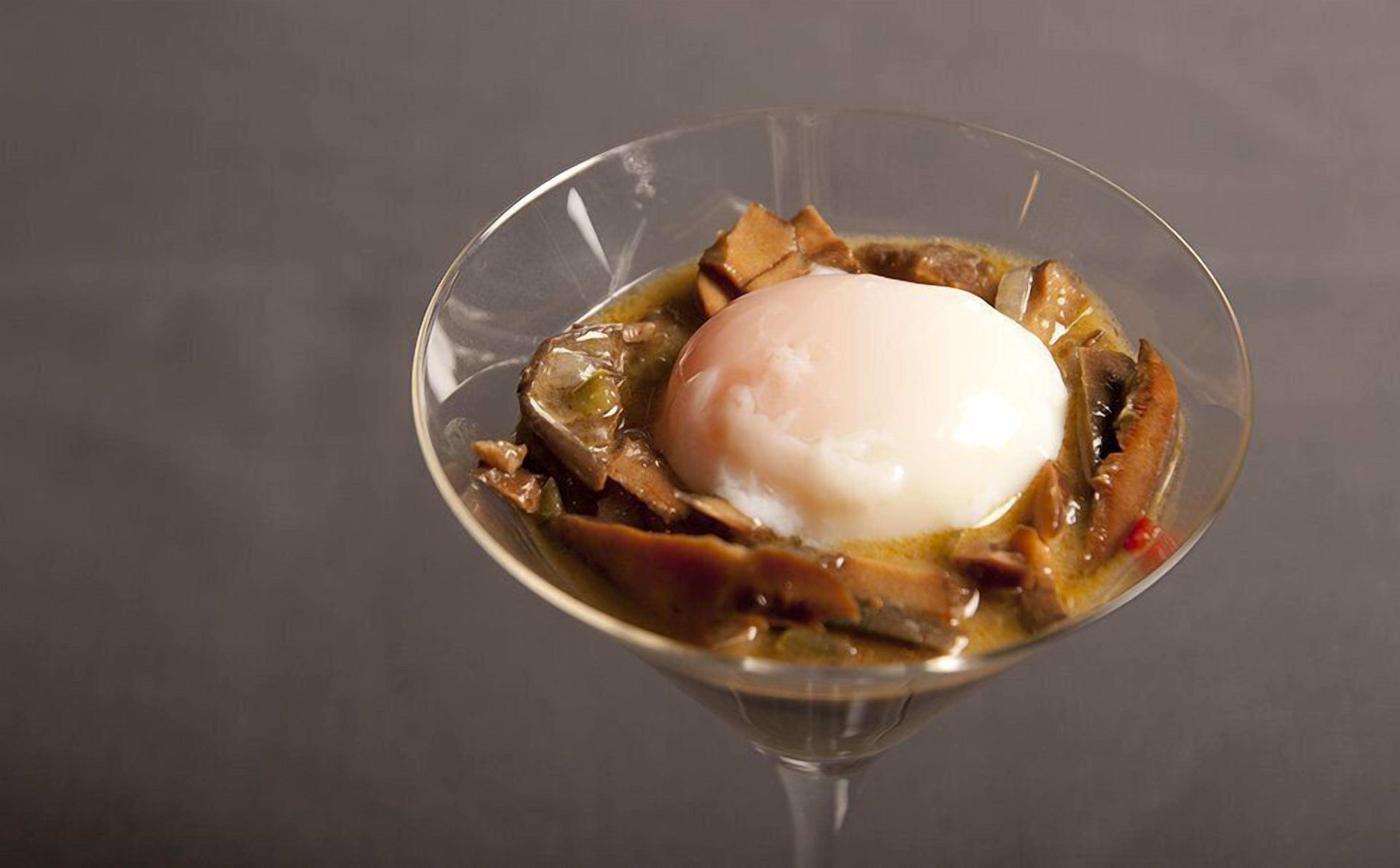 Postre en una copa de vidrio transparente con un huevo pochado encima.