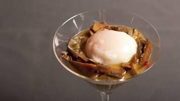 Postre en una copa de vidrio transparente con un huevo pochado encima.