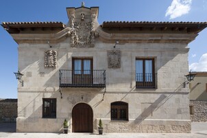 Um edifício histórico com entrada central, duas varandas e detalhes em pedra decorativa.