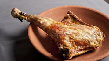 Pierna de cordero asada sobre un plato de terracota.