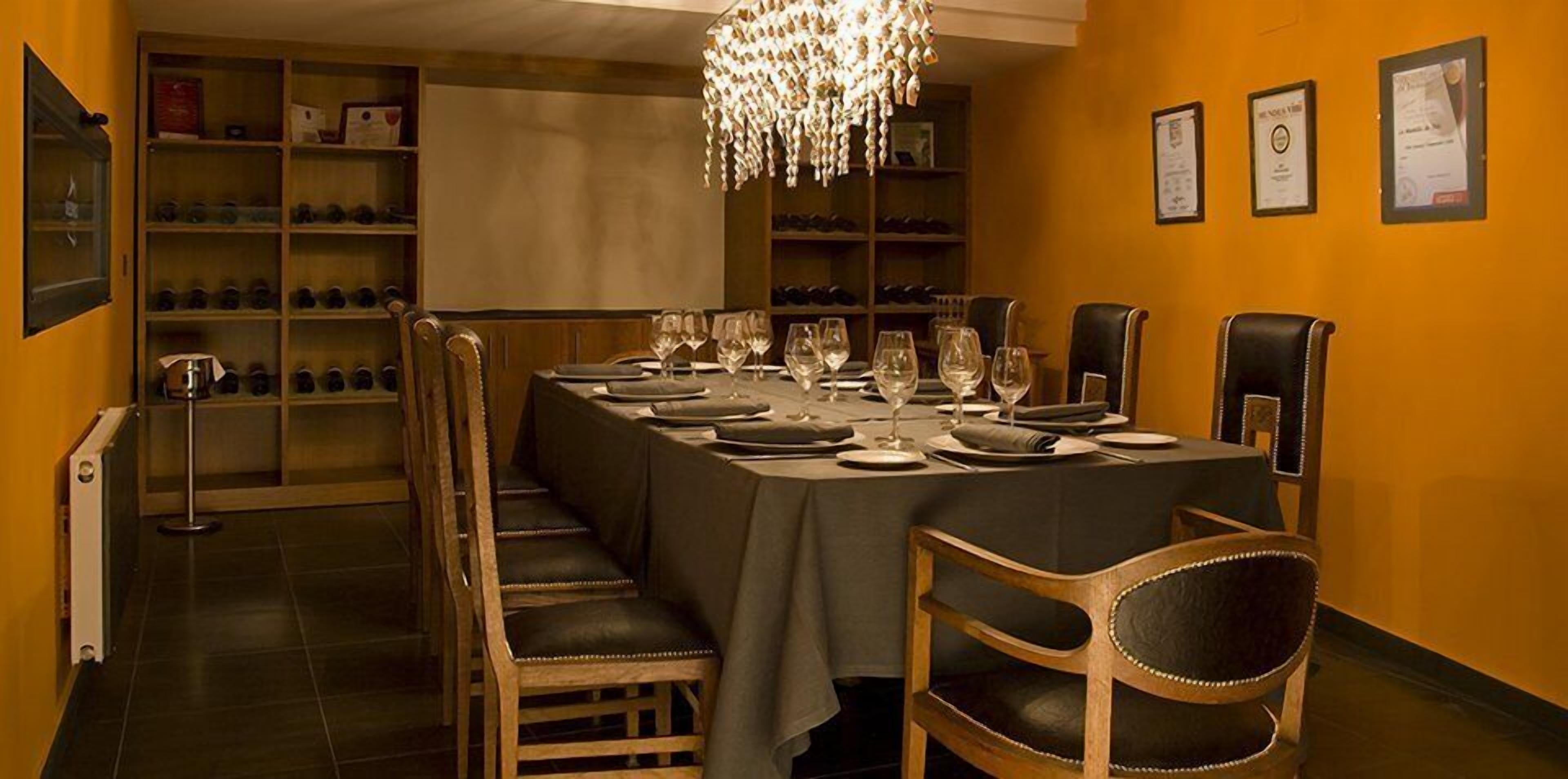 Un comedor con una larga mesa dispuesta para una comida, rodeada de sillas de madera.