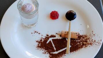 Un plat blanc amb un postre que consisteix en una bola de gelat, una frambuesa i una cirera amb cobertura de xocolata en un pal.