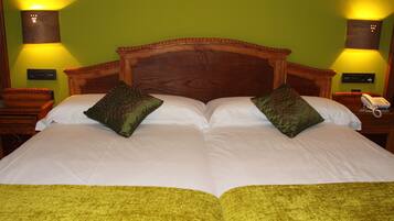 Una cama doble con dos almohadas, cabecera de madera y colcha verde.