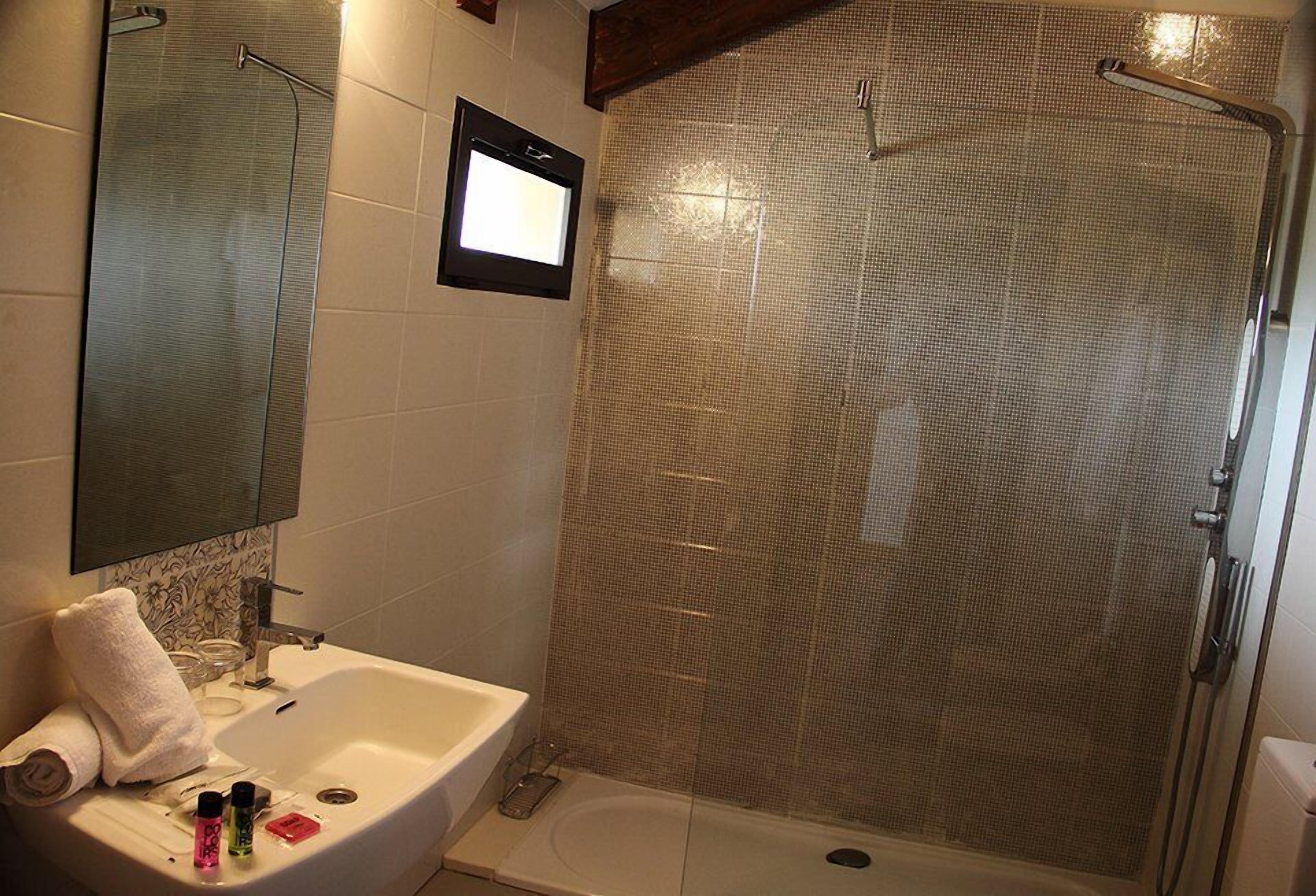 A bathroom with a shower, sink, and mirror.