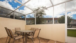 A covered patio with a table and chairs, a view of houses and trees, and a clear sky. - Ip60384 - Fiesta Key - 3 Bed 2.5 Baths Townhome (Kissimmee)