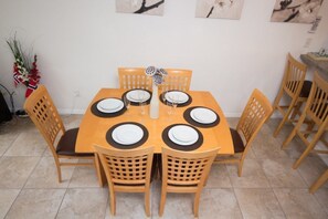 A dining table set for six with wooden chairs, a vase with flowers, and artwork on the wall. - Ip60384 - Fiesta Key - 3 Bed 2.5 Baths Townhome (Kissimmee)