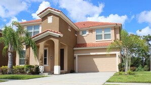 A two-story house with a red-tiled roof, beige exterior walls, and a garage. - Aco63671 - Bella Vida Resort - 6 Bed 5.5 Baths Villa (Kissimmee)