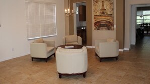 A living room with a fireplace, beige sofas, and a chandelier. - Aco63671 - Bella Vida Resort - 6 Bed 5.5 Baths Villa (Kissimmee)