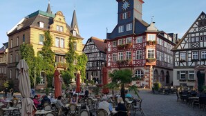 Una plaza empedrada con mesas al aire libre y edificios tradicionales de entramado de madera.