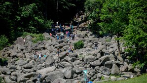 Un espacio al aire libre rocoso con gente caminando y parada.