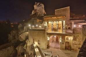 A historic building with a stone facade, arched doorways, and a balcony with railings. - Abu Hayat Cave Suites (Ürgüp)