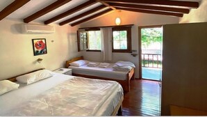 A bedroom with two beds, wooden beams on the ceiling, a window, and a door leading outside. - Montenegro Motel (Fethiye)