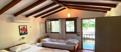 Un dormitorio con dos camas, vigas de madera en el techo, una ventana y una puerta que da al exterior.
