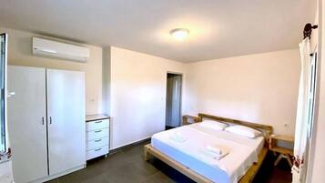 Un dormitorio con cama, armario, mesita de noche y aire acondicionado.
