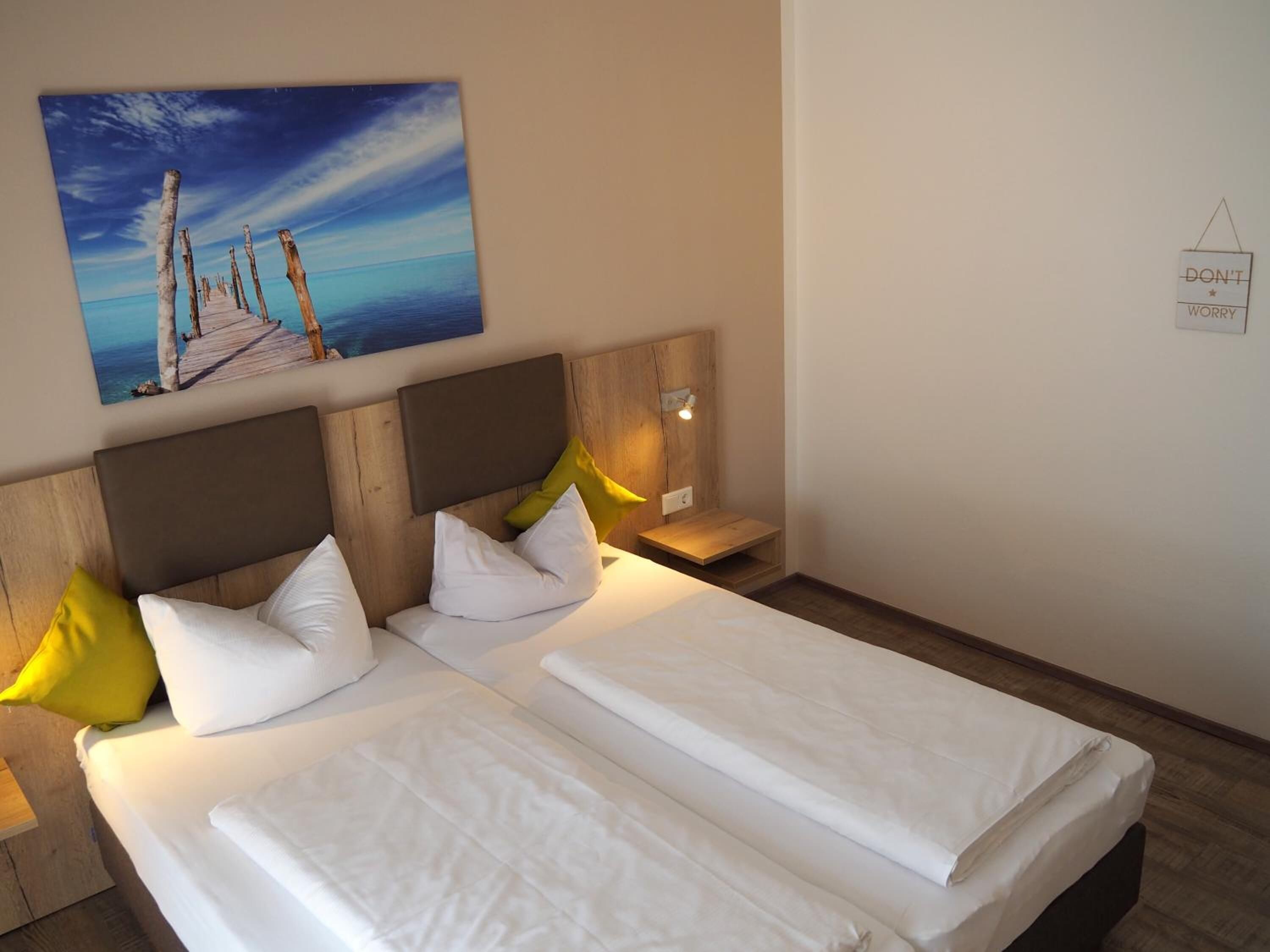 A double bed with white linens, wooden headboard, and two bedside tables with lamps.