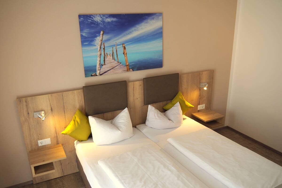 A double bed with white linens, wooden headboard, and two bedside tables with lamps.