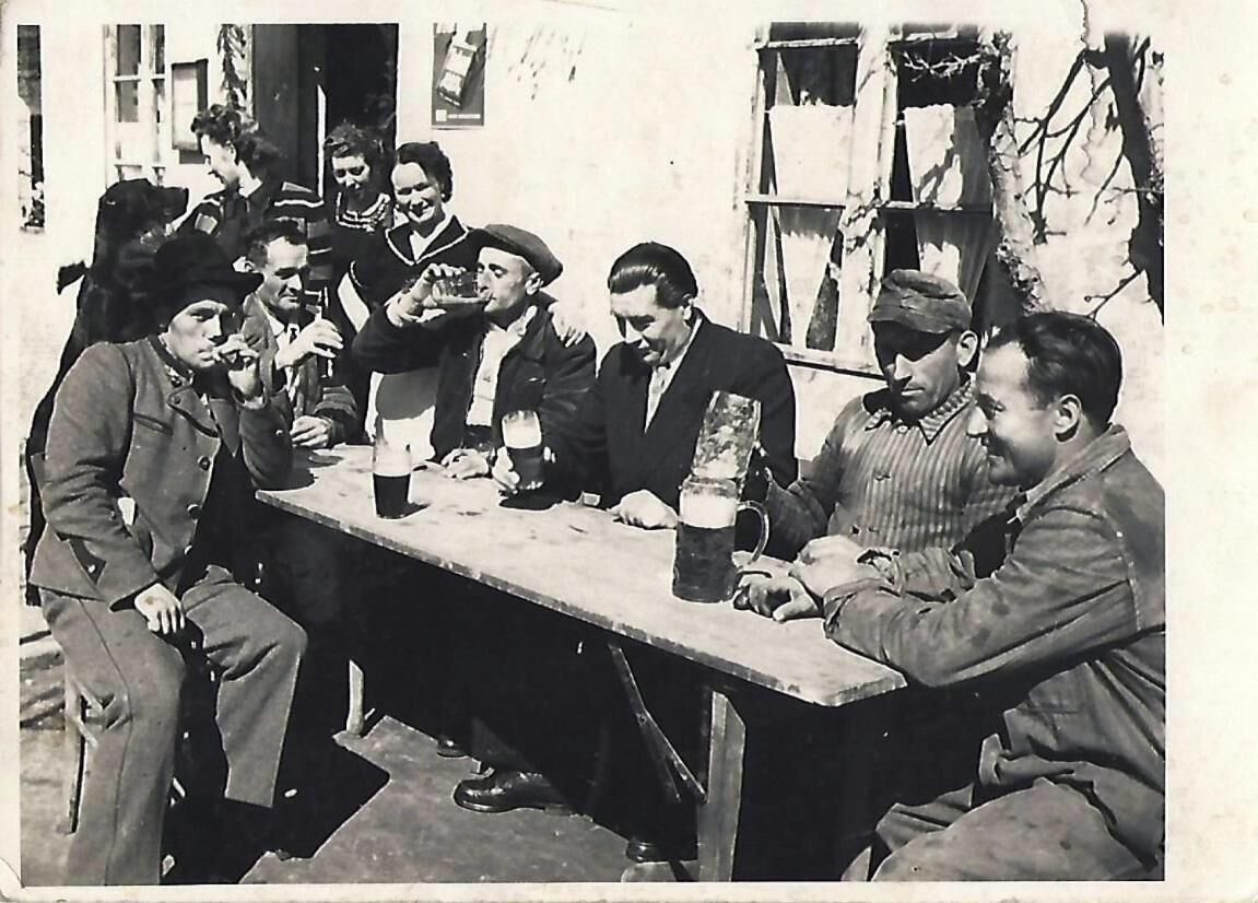 A group of men sitting around a table outdoors, engaged in conversation.