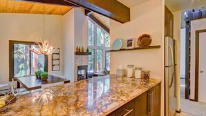 A modern kitchen with a granite countertop, stainless steel appliances, and a large window offering a view of the outdoors. - Tannenbaum By The River 2 Bedroom Condo by RedAwning (Breckenridge)