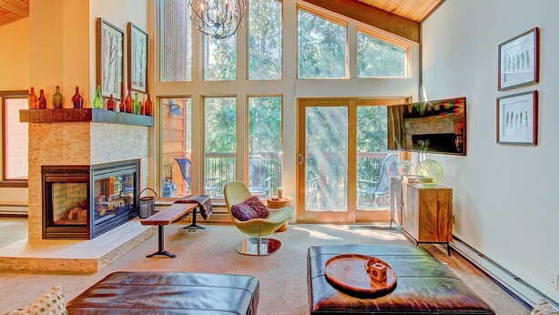 A spacious living room with large windows, a fireplace, and modern furniture. - Tannenbaum By The River 2 Bedroom Condo by RedAwning (Breckenridge)