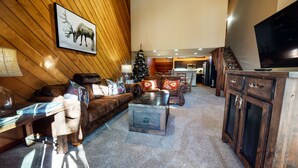 Ein gemütliches Wohnzimmer mit Holzbalkendecke, Kamin, Weihnachtsbaum und Fernseher.
