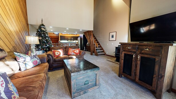 Ein Wohnzimmer mit Ledersofa, Couchtisch, Holzschrank, Fernseher und Weihnachtstanne.