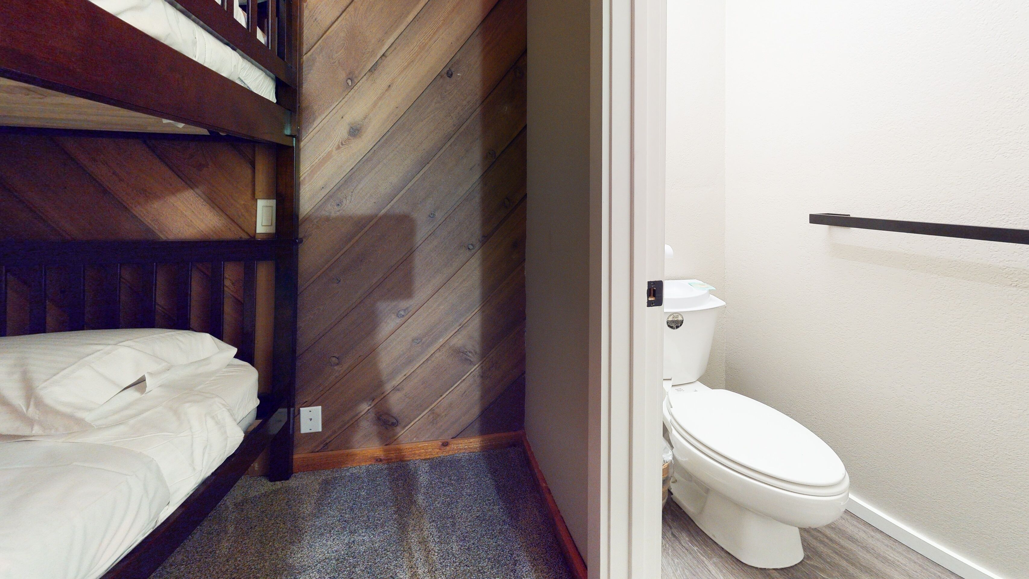 Ein kleiner, kompakter Raum mit einem Etagenbett, einer Toilette und einer Holzwand.