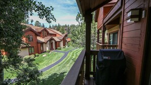 Eine Holterrasse mit Grill, mit Blick auf einen gepflegten Rasen und ein Haus mit rotem Dach.