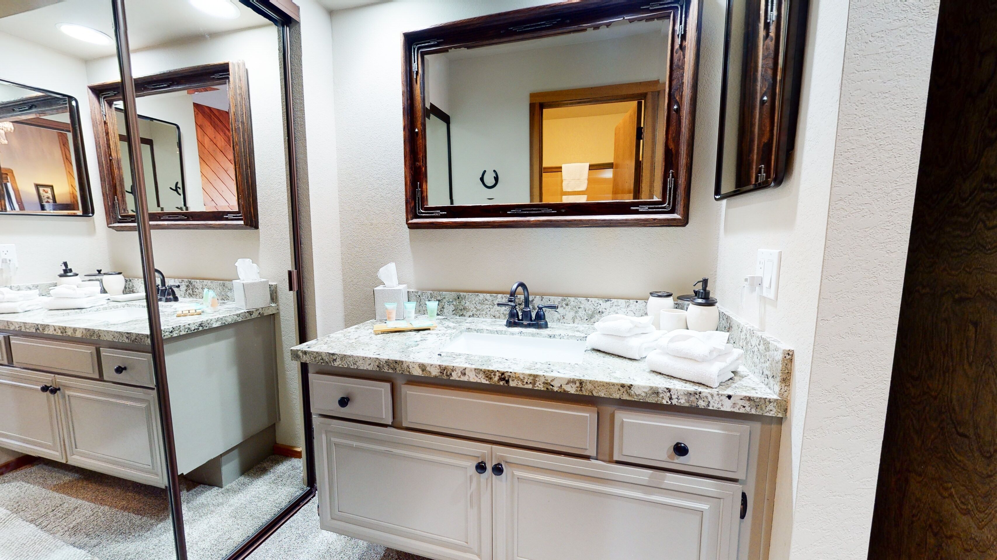 A bathroom with two sinks, each with a mirror above. There are towels and toiletries on the counters.