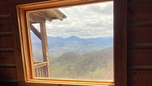 Une chambre de cabane dotée d’une grande fenêtre donnant sur un paysage montagneux.
