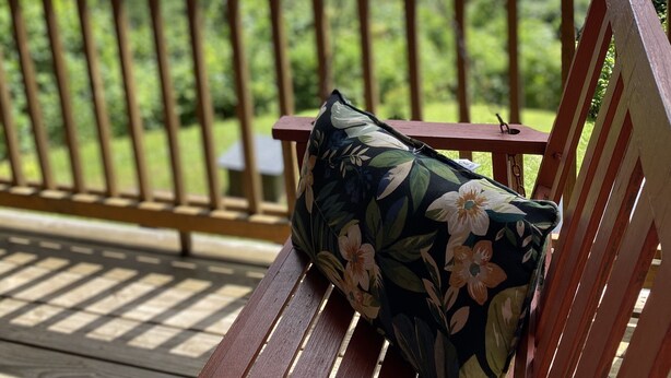 Une terrasse en bois avec un banc et une balançoire suspendue.
