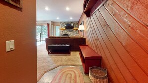 A cozy living room with a stone fireplace, a television, and a wooden bench. - Snowcreek II 247 Pet-Friendly, Cozy, On the Snowcreek Meadow by RedAwning (Mammoth Lakes)