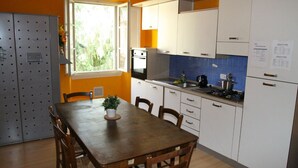 A compact kitchen with white cabinets, a wooden dining table, and a window providing natural light.