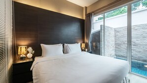 A modern bedroom with a large bed, a nightstand with a lamp, and a view of a swimming pool through glass doors. - AnB Pool Villa Modern 3BR at The Ville Jomtian Pattaya (Pattaya)