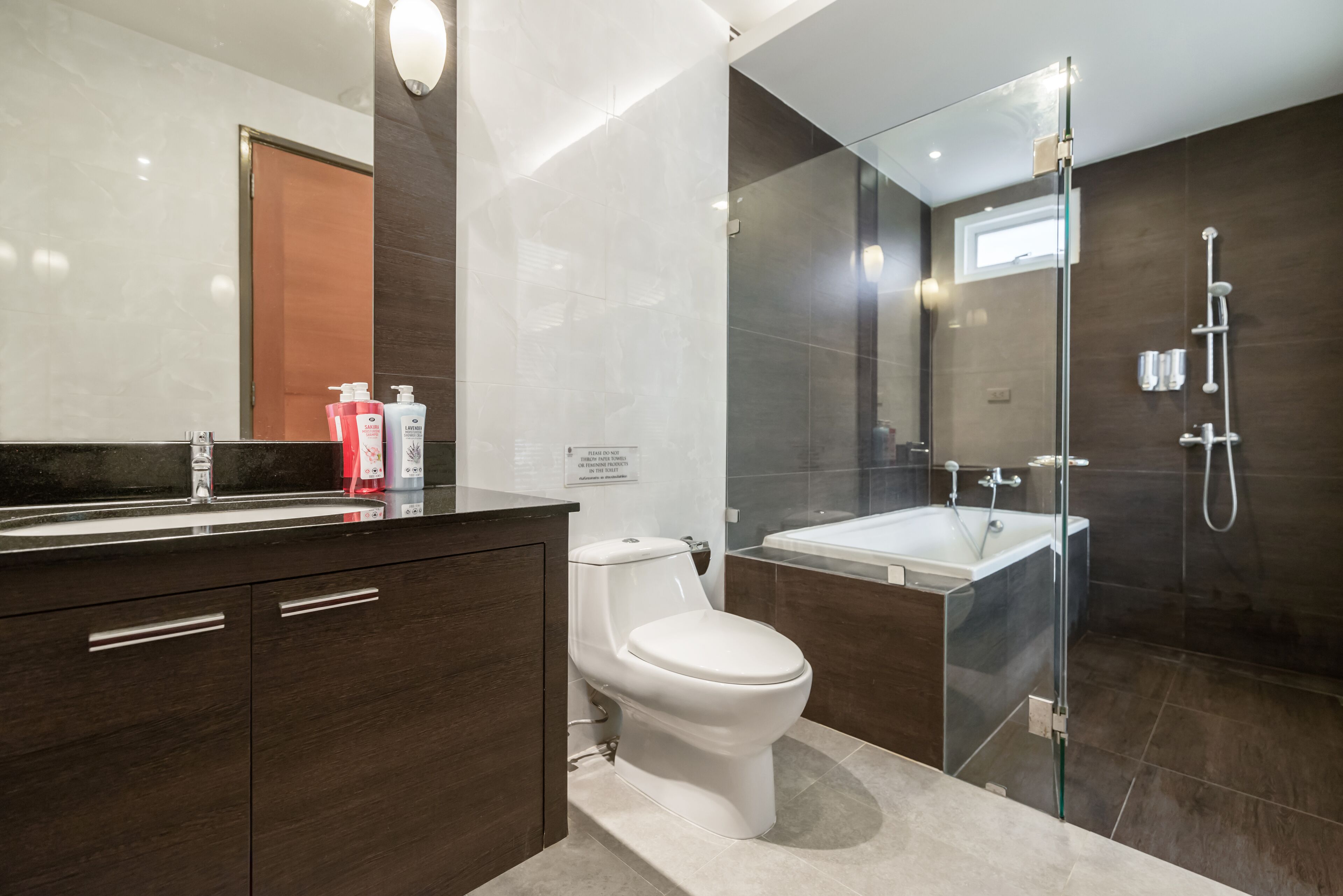 Ein modernes Badezimmer mit Toilette, einer Glaskabine zur Dusche und einer Badewanne.