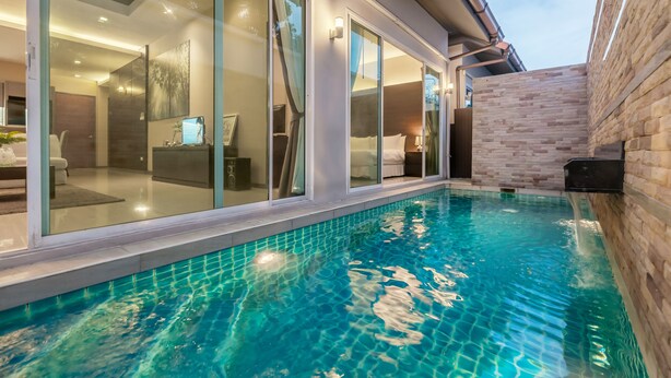 A modern hotel with a swimming pool, large glass windows, and a brick exterior wall. - AnB Pool Villa Modern 3BR at The Ville Jomtian Pattaya (Pattaya)