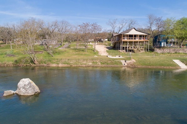 A lakeside building with a dock, surrounded by trees and a grassy area.